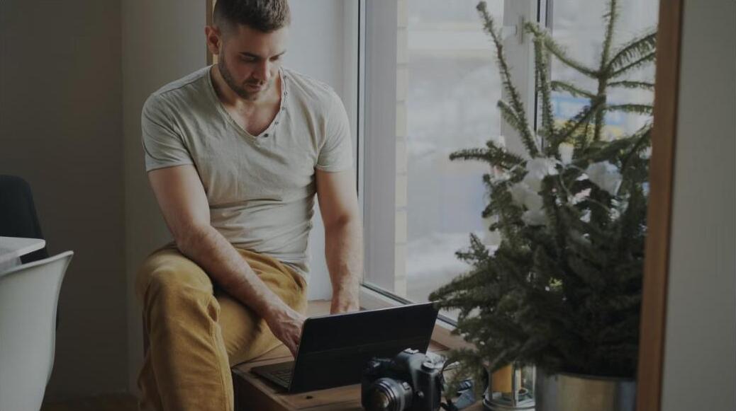 A self-employed professional working on a laptop by a sunny window